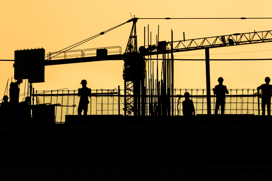 Construction workers working on a site witth a crane in the background