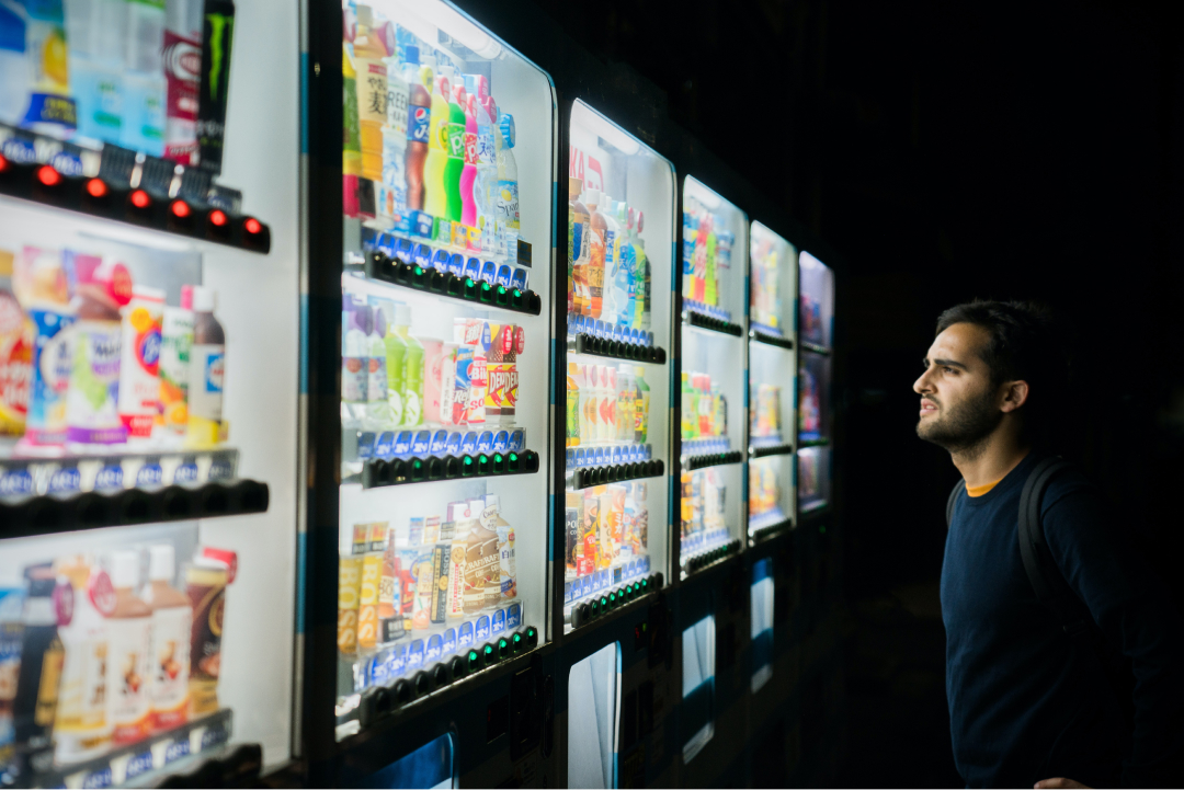 A man hesitating in front of vending machines